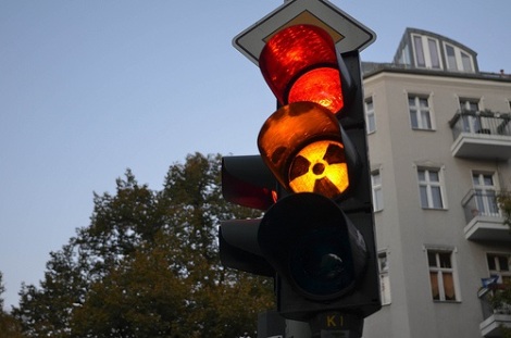 Traffic lights with red and amber lit up and a radioactivity sign on the amber.